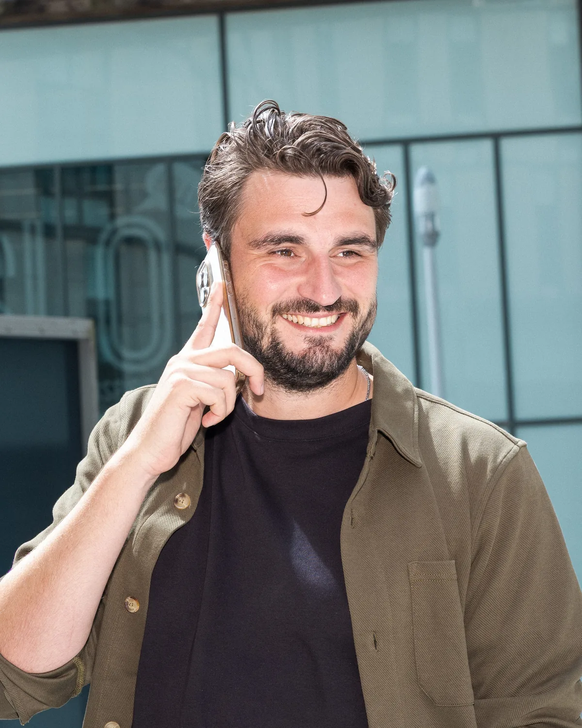 Collega van PROMPTED voert lachend een telefoongesprek buiten het kantoor